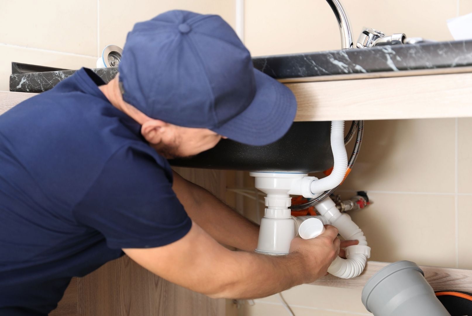 A plumber is fixing a sink in a bathroom.