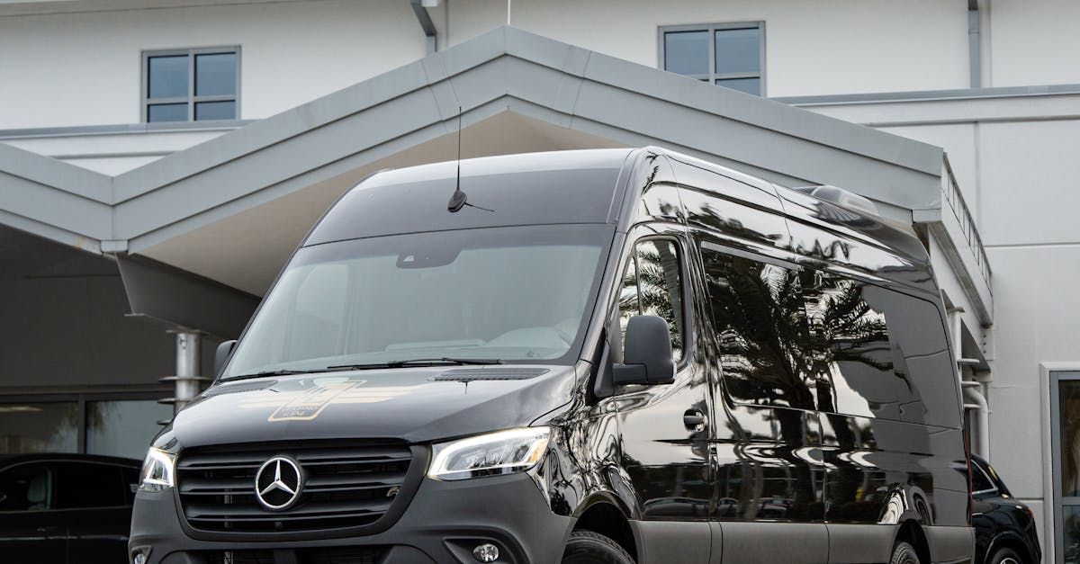 A black mercedes sprinter van is parked in front of a building.