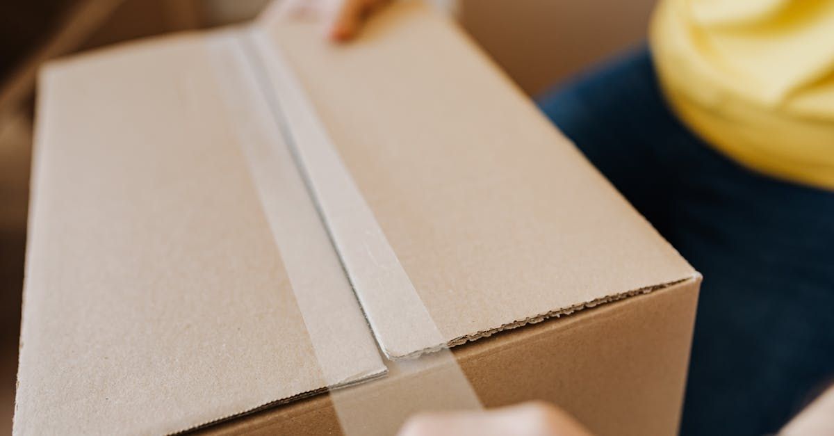 A person is taping a cardboard box with tape.