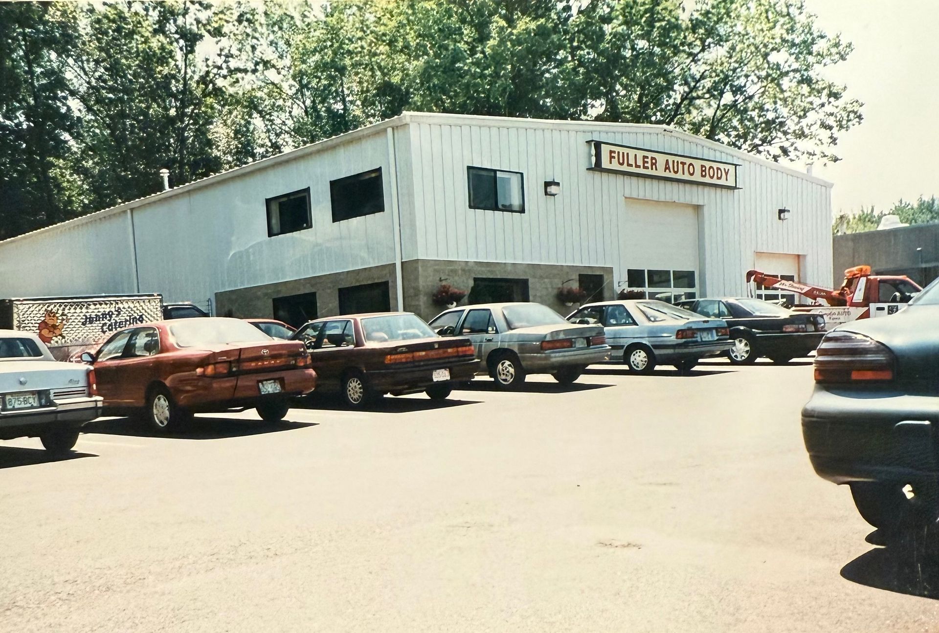 A row of cars are parked in front of a building that says full auto care