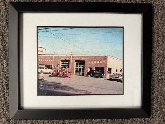 A framed picture of a junkyard with cars parked in front of it