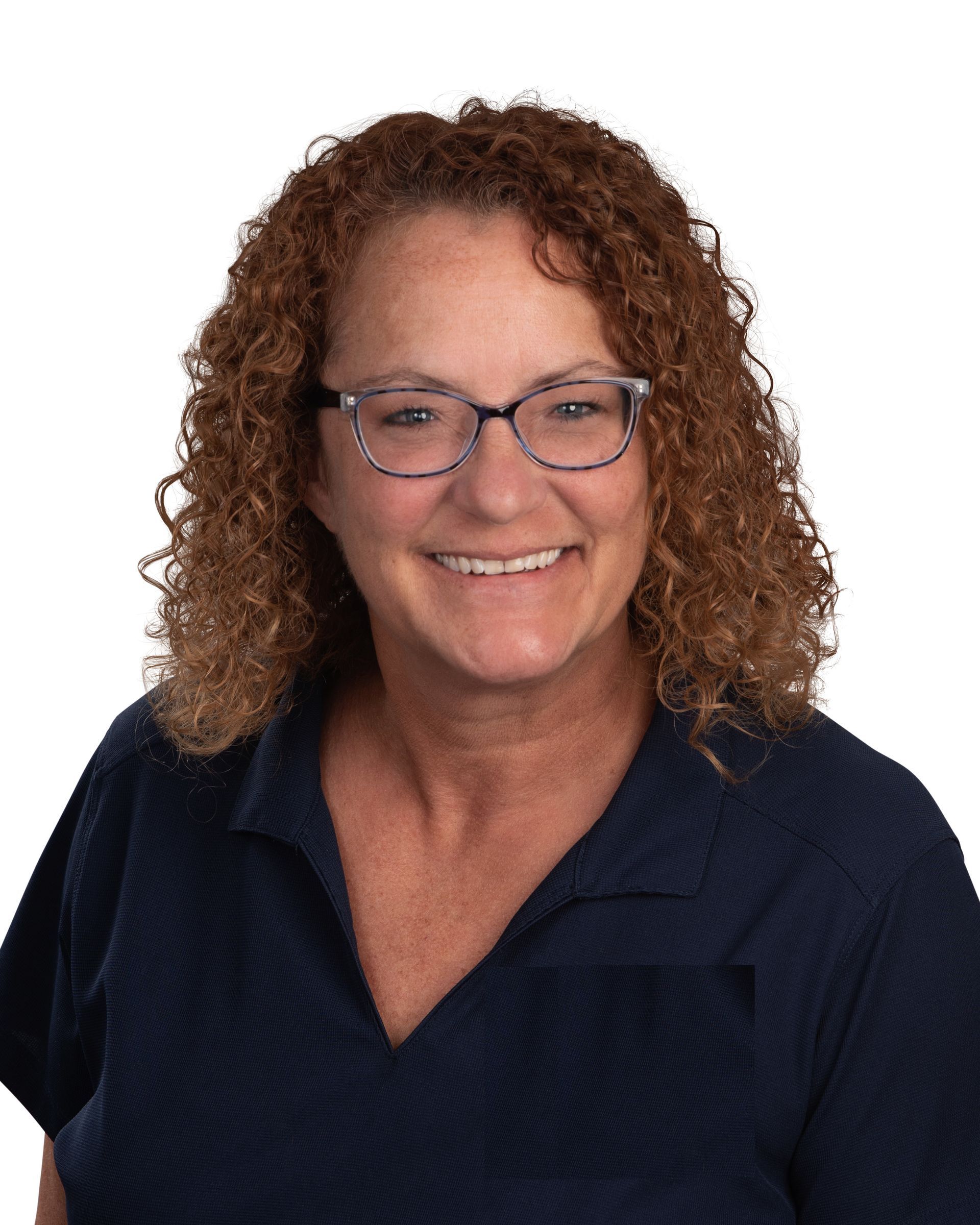 A woman wearing glasses and a blue shirt is smiling for the camera.