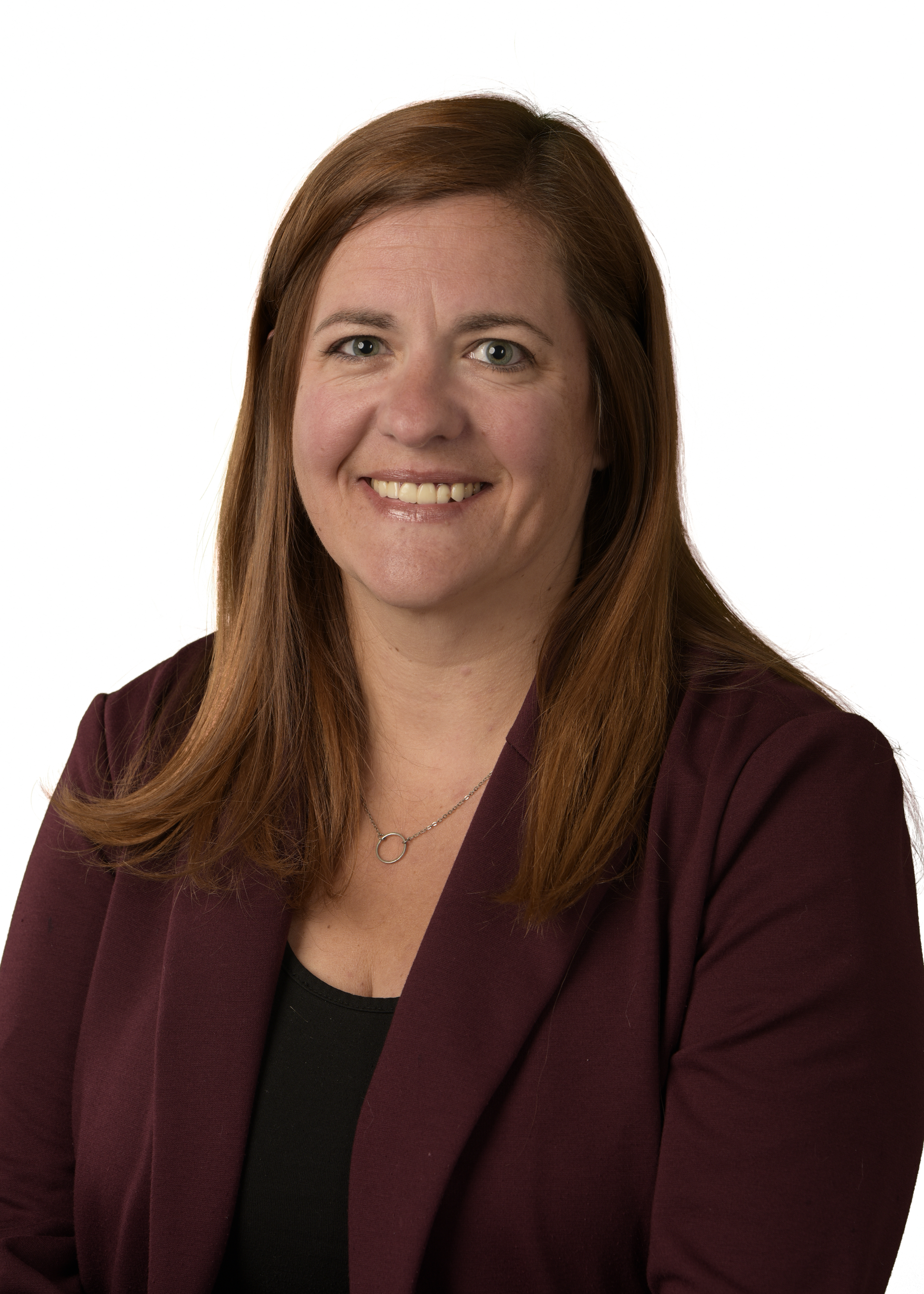 A woman wearing glasses and a blue shirt is smiling for the camera.