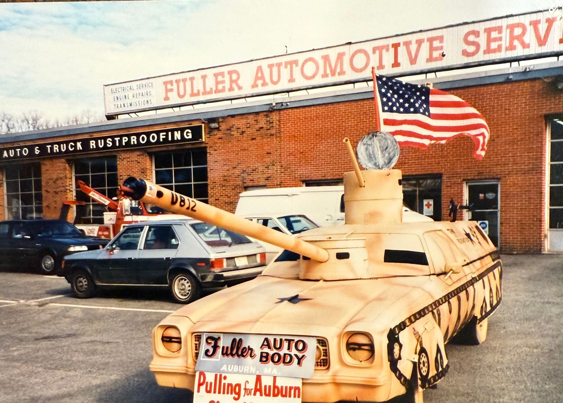 A car that looks like a tank is parked in front of a fuller automotive service