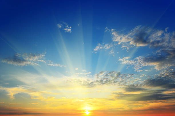 The sun is shining through the clouds at sunset.