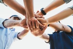 A group of people are putting their hands together in a circle.