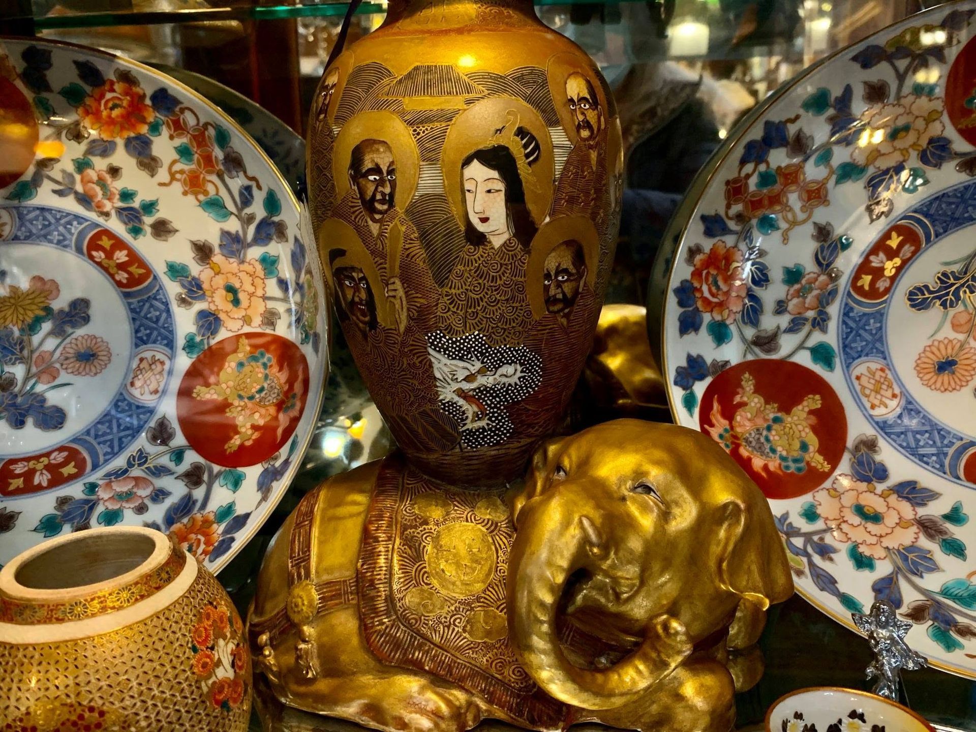 Decorative porcelain dishes and a gold Buddha head statue with floral patterns and ornate designs