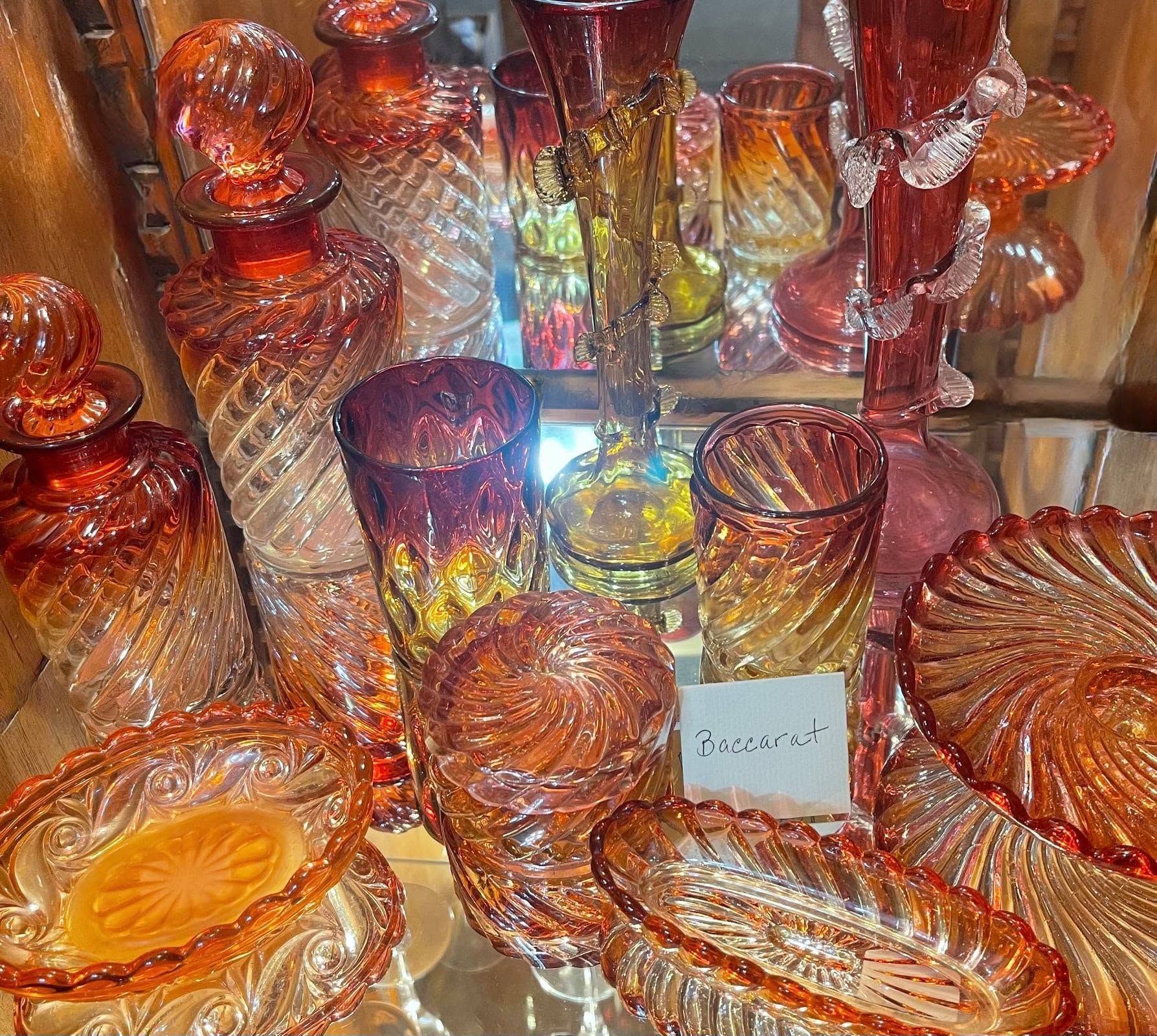 Assorted amber and red glass decorative bowls and vases displayed closely together under bright light