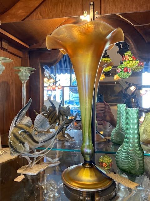 Glass art display with a tall amber vase, green vase, and shell sculpture in a wooden room