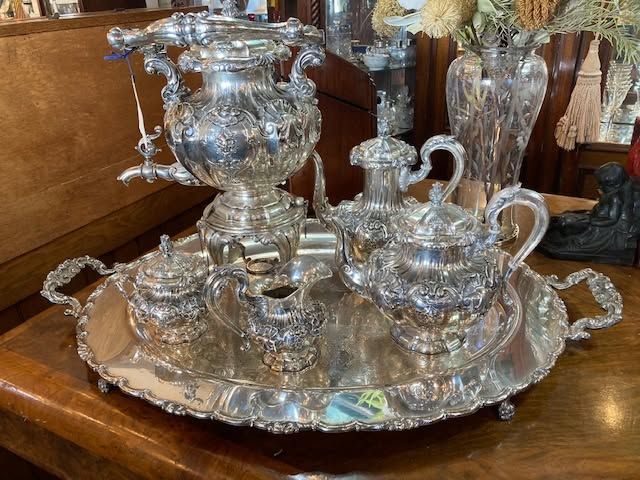 Silver tea set on ornate tray on a wooden table
