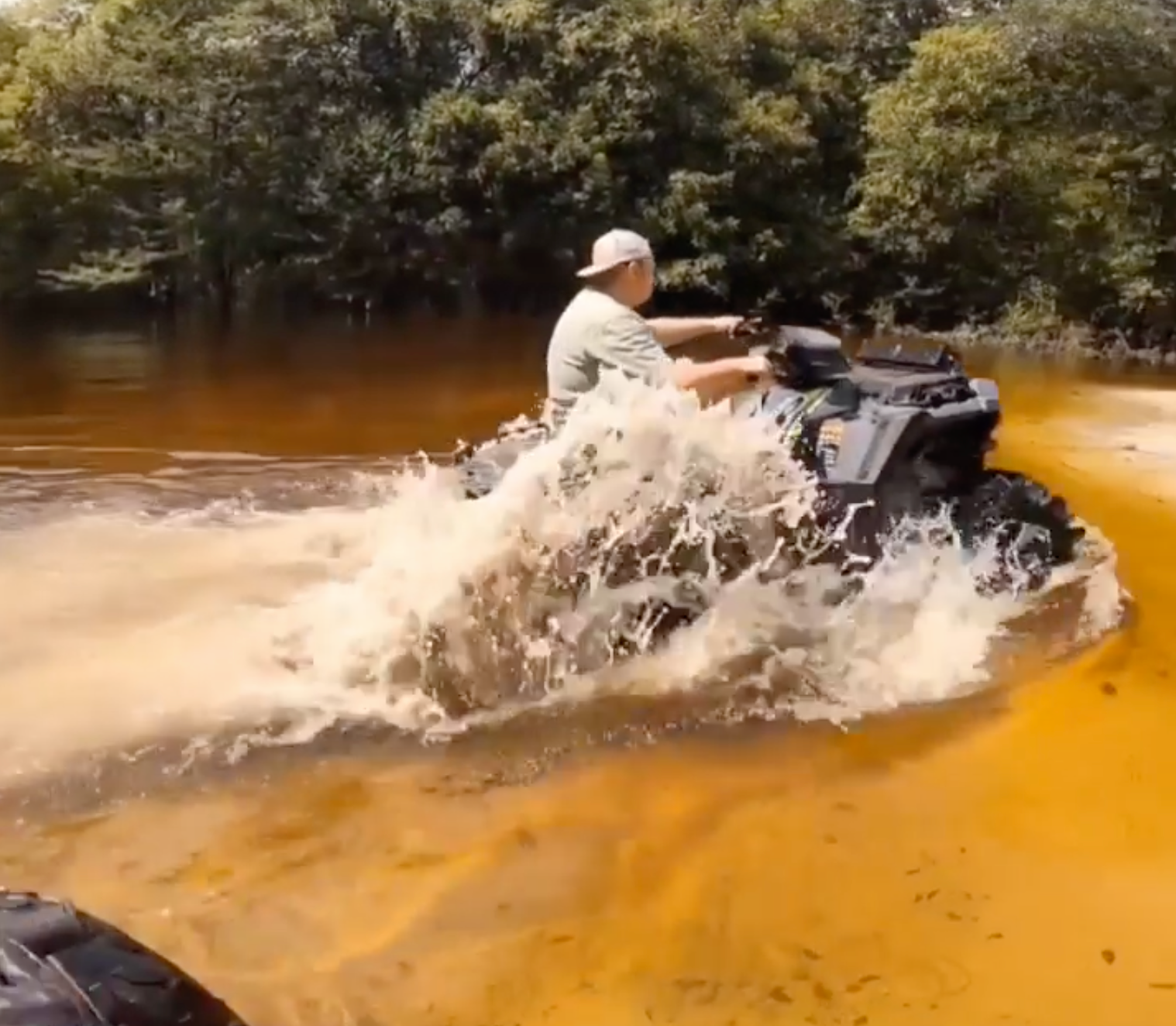 a man is riding a four wheeler through a muddy river .