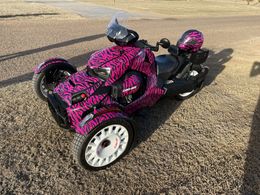 A pink and black motorcycle is parked on the side of the road.