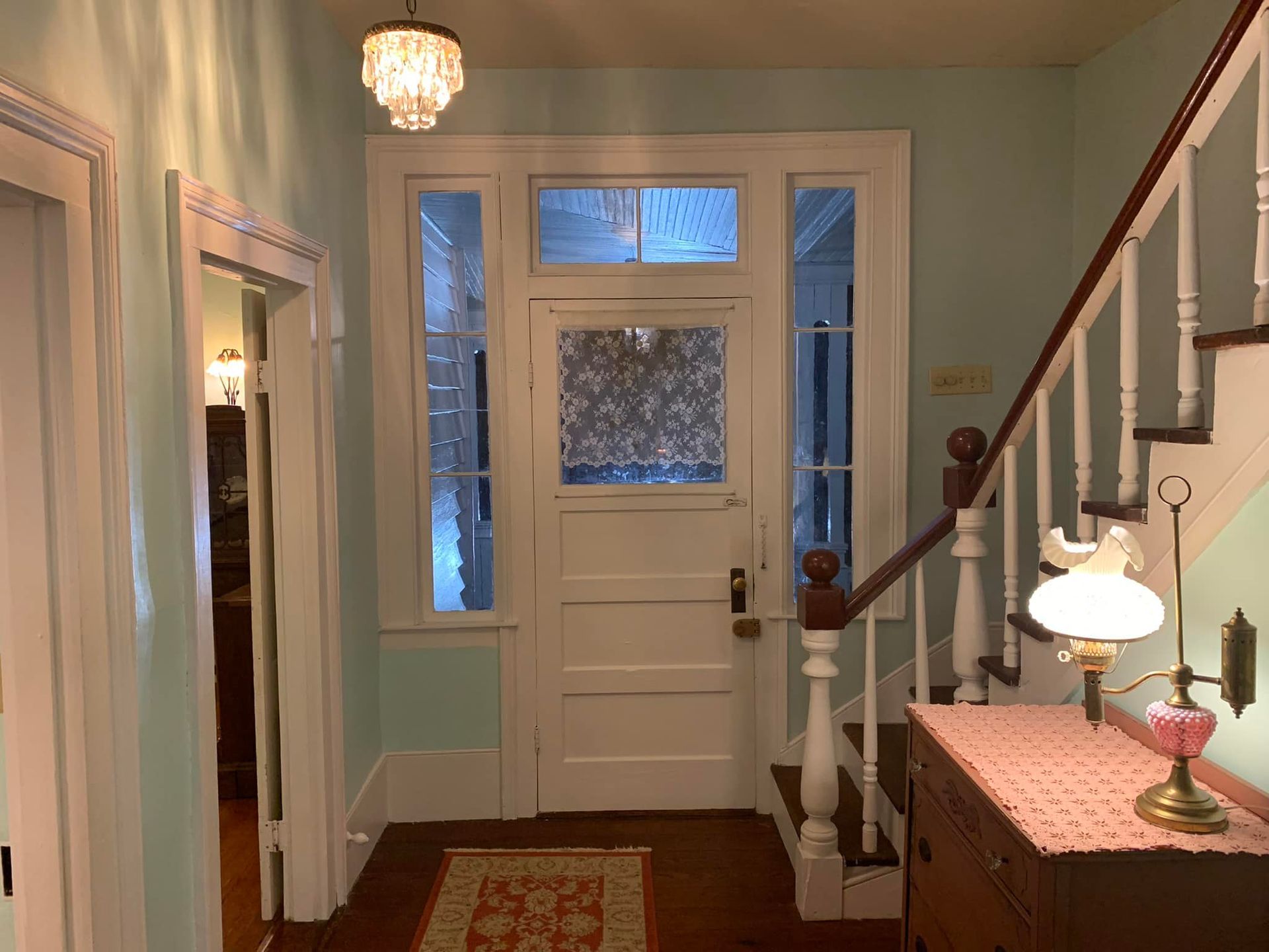 A hallway with stairs leading up to the front door of a house.