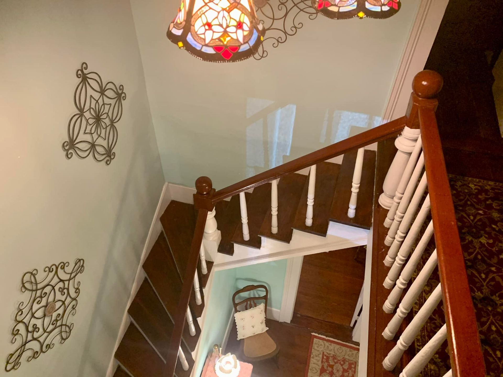 A staircase with a stained glass lamp hanging from the ceiling