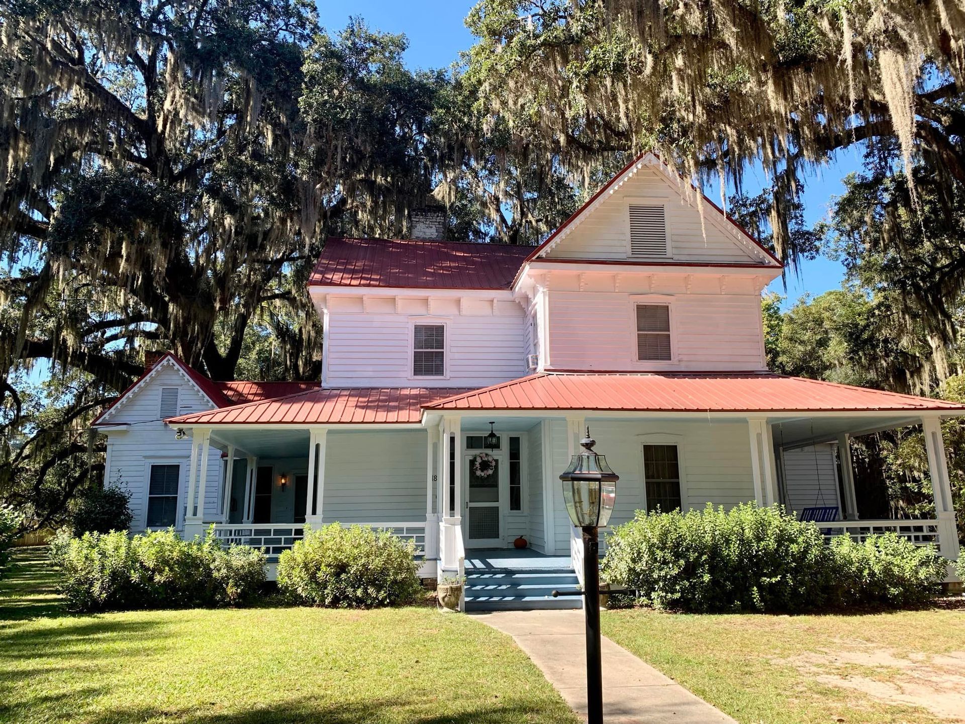 A white house with a red roof and a porch