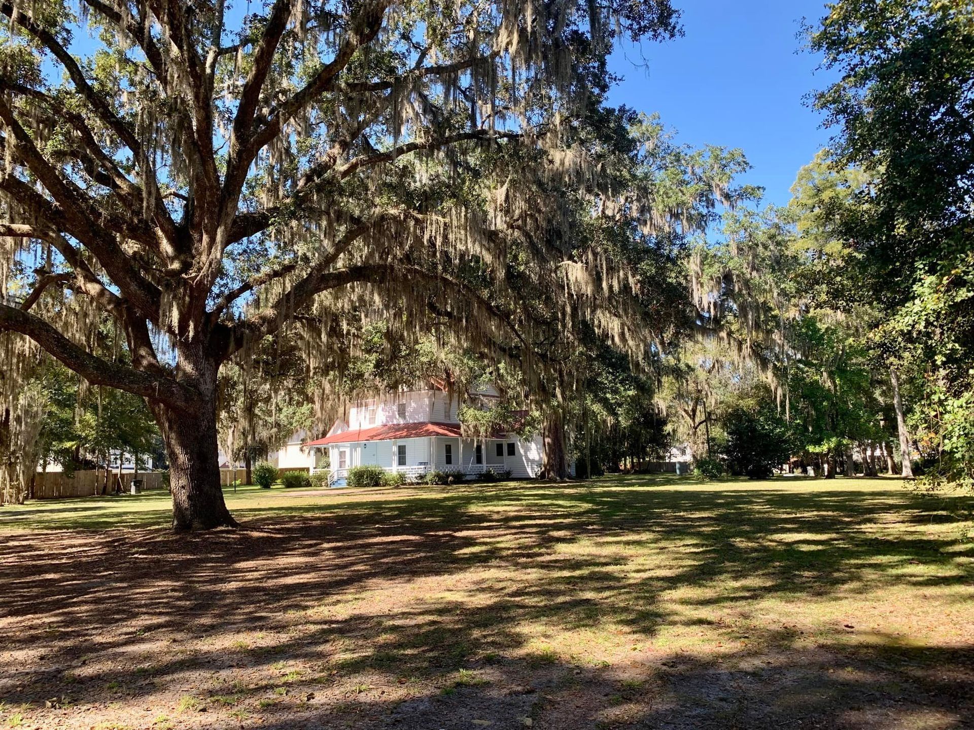 A house is surrounded by trees and grass in a large yard.