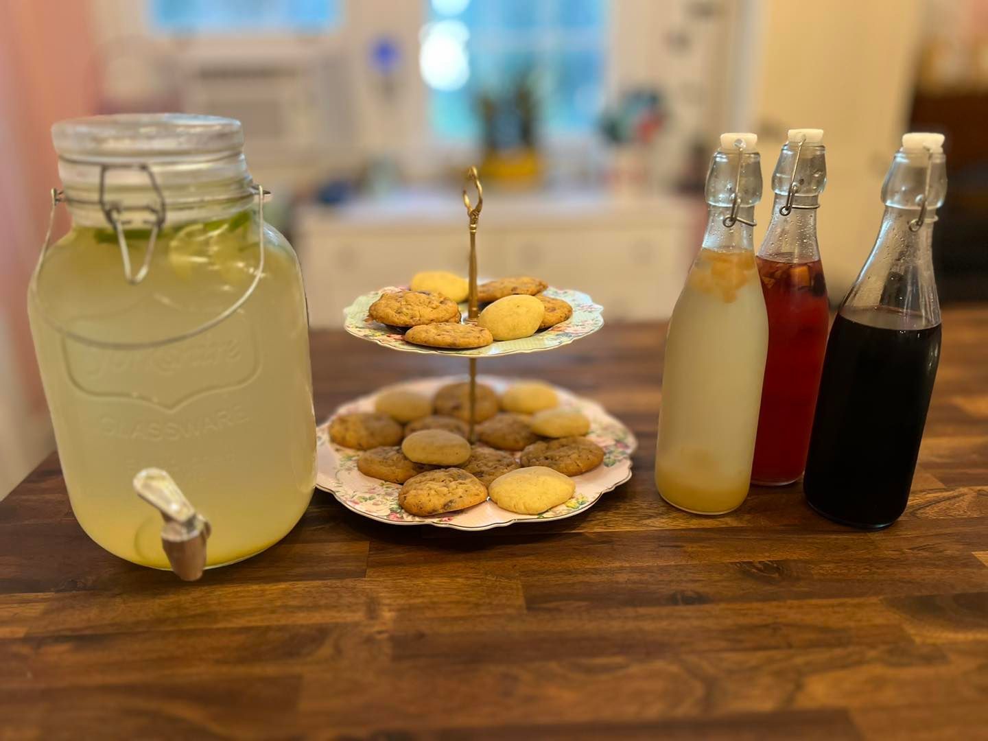 A table with a jar of lemonade and a plate of cookies