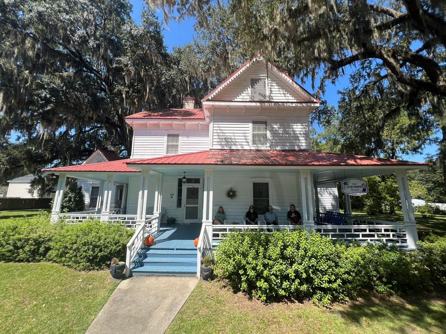 A white house with a red roof and a large porch.
