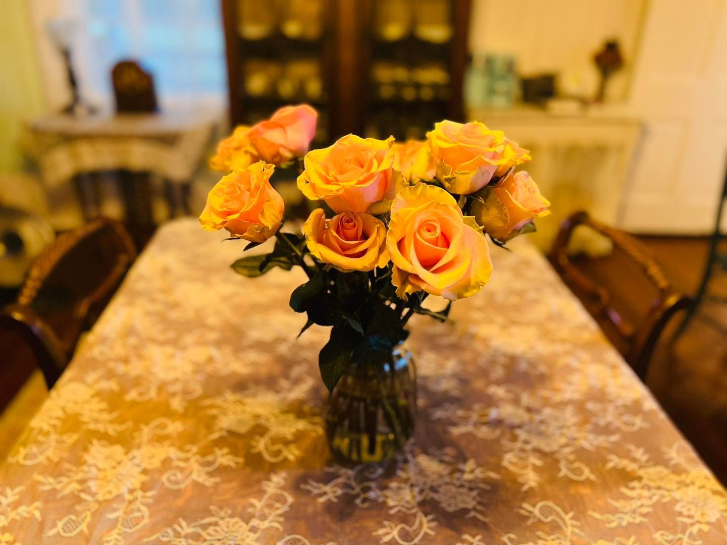 A vase filled with yellow roses is sitting on a table.