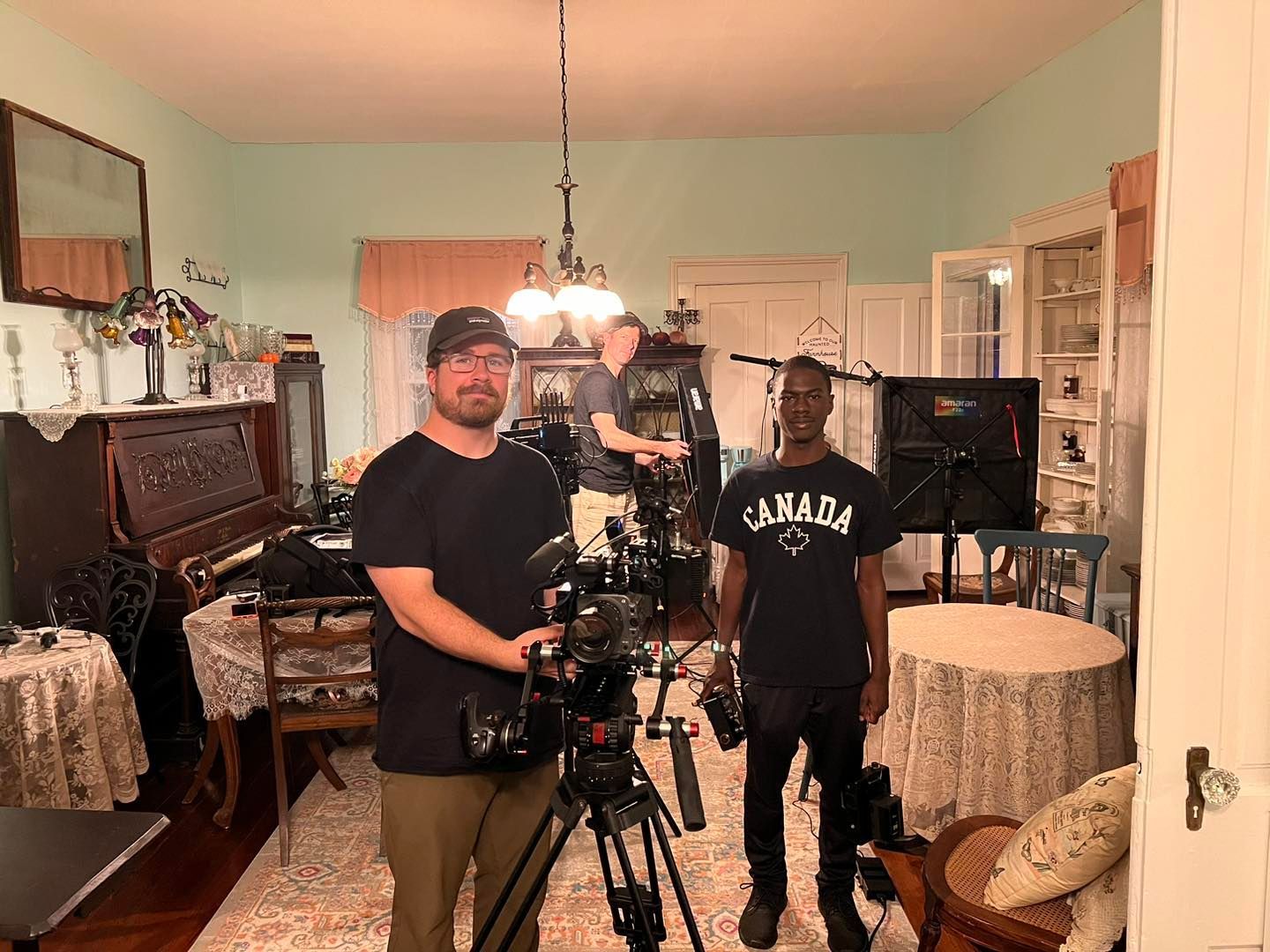 Two men are standing in a living room holding cameras.