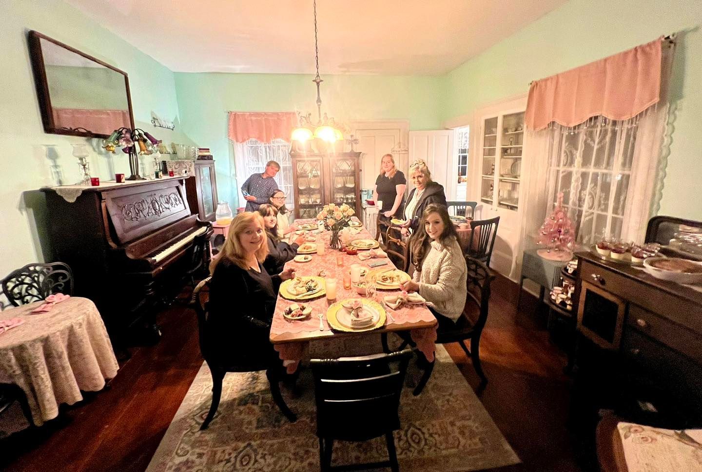 A group of people are sitting at a long table in a dining room.