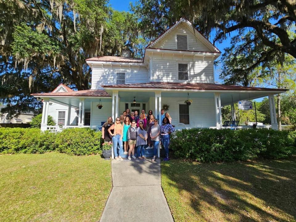 A group of people are posing for a picture in front of a white house.