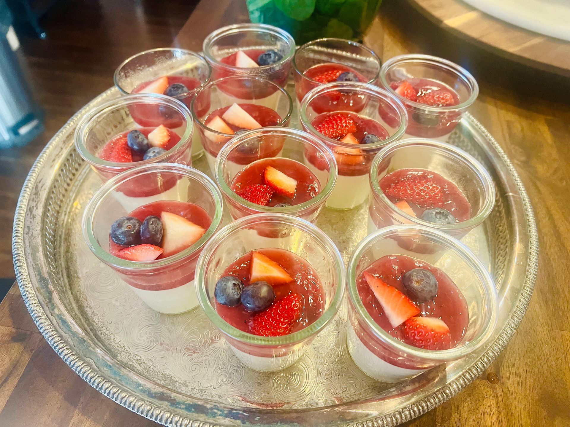 A tray of desserts with strawberries and blueberries on a wooden table.