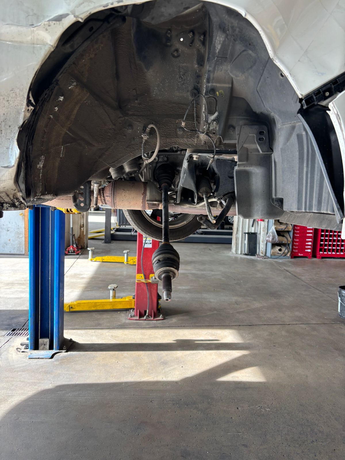 Car raised on a lift in an auto repair shop, with the undercarriage exposed. | Buck & Doe Auto