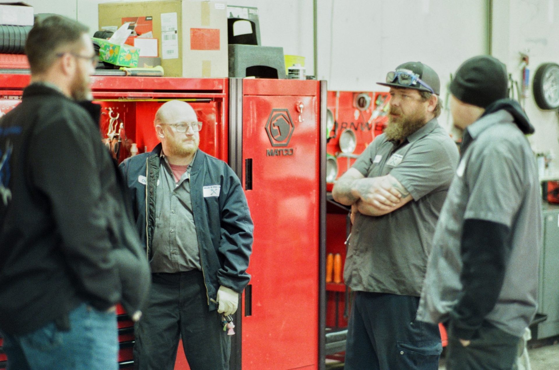 People standing and talking in front of red vending machines in an indoor setting | Buck & Doe Auto
