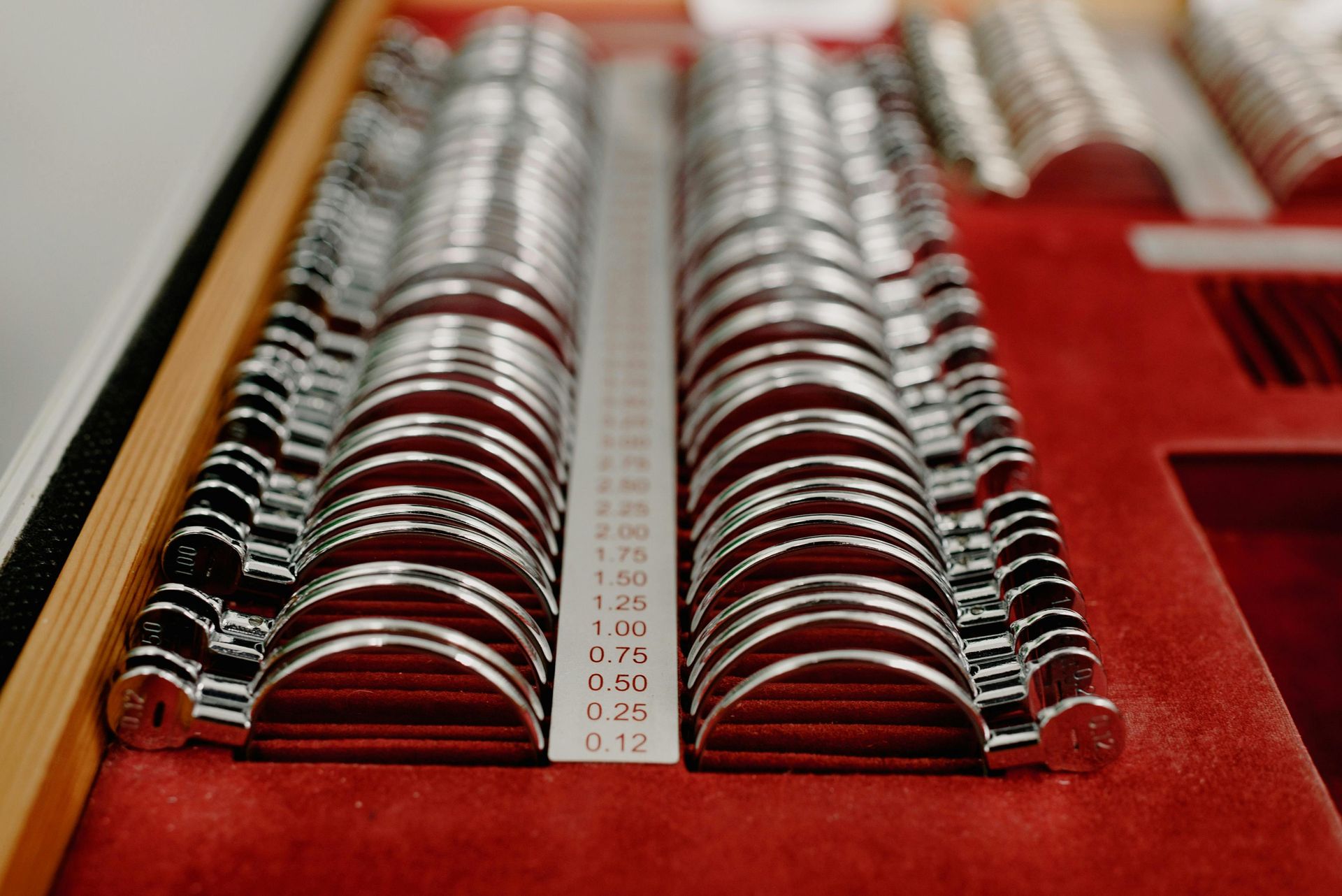 Rows of polished metal weights in a red velvet-lined case, arranged by size