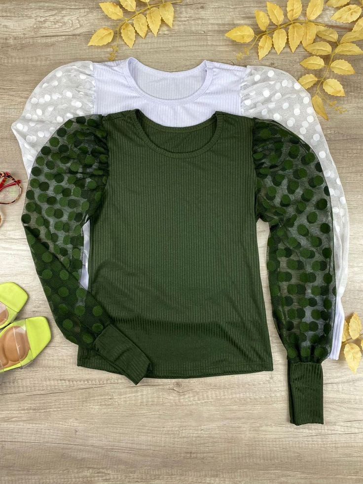 Un suéter verde con mangas de lunares y un suéter blanco con mangas de lunares sobre una mesa de madera.