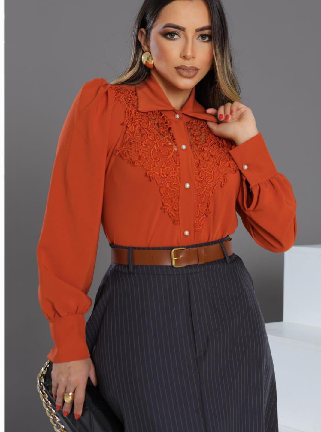 Una mujer lleva una camisa naranja y una falda negra.