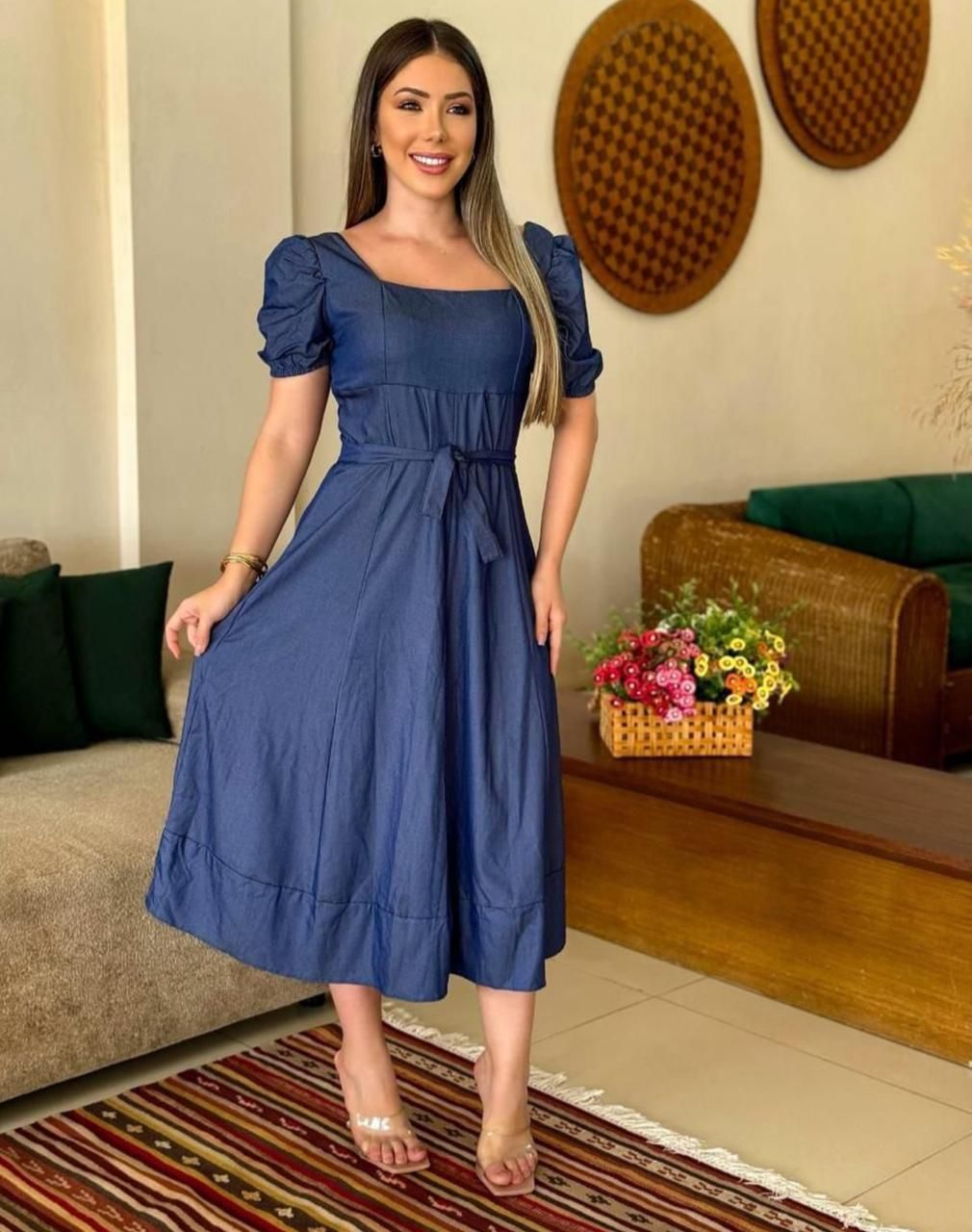Una mujer con un vestido azul está parada en una sala de estar.