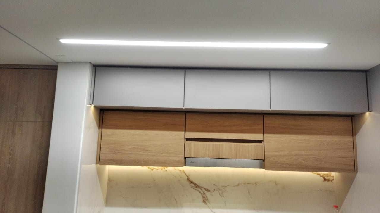 Muebles de cocina en tonos grises y madera con iluminación de tira.