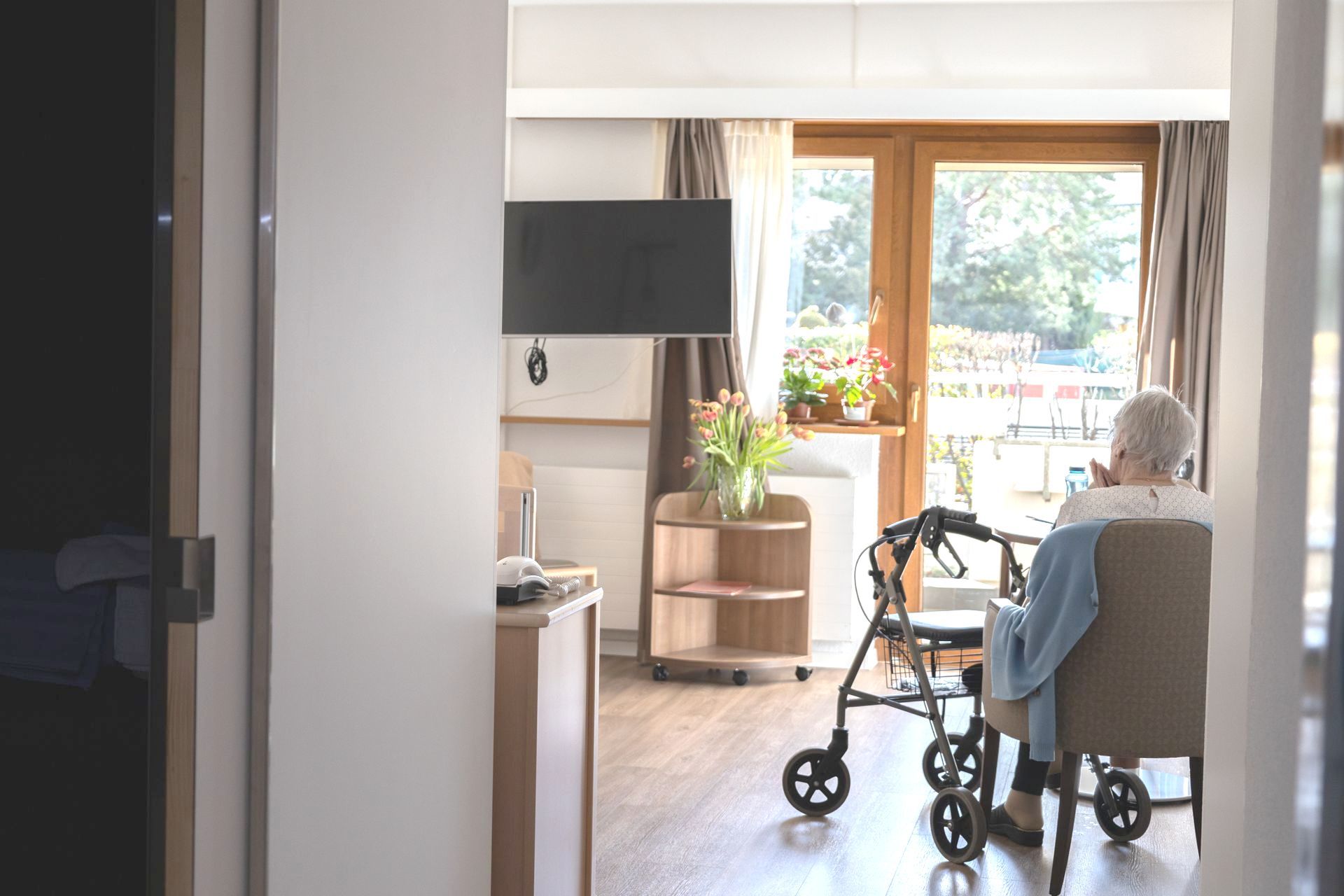 une femme âgée est assise sur une chaise dans la chambre.