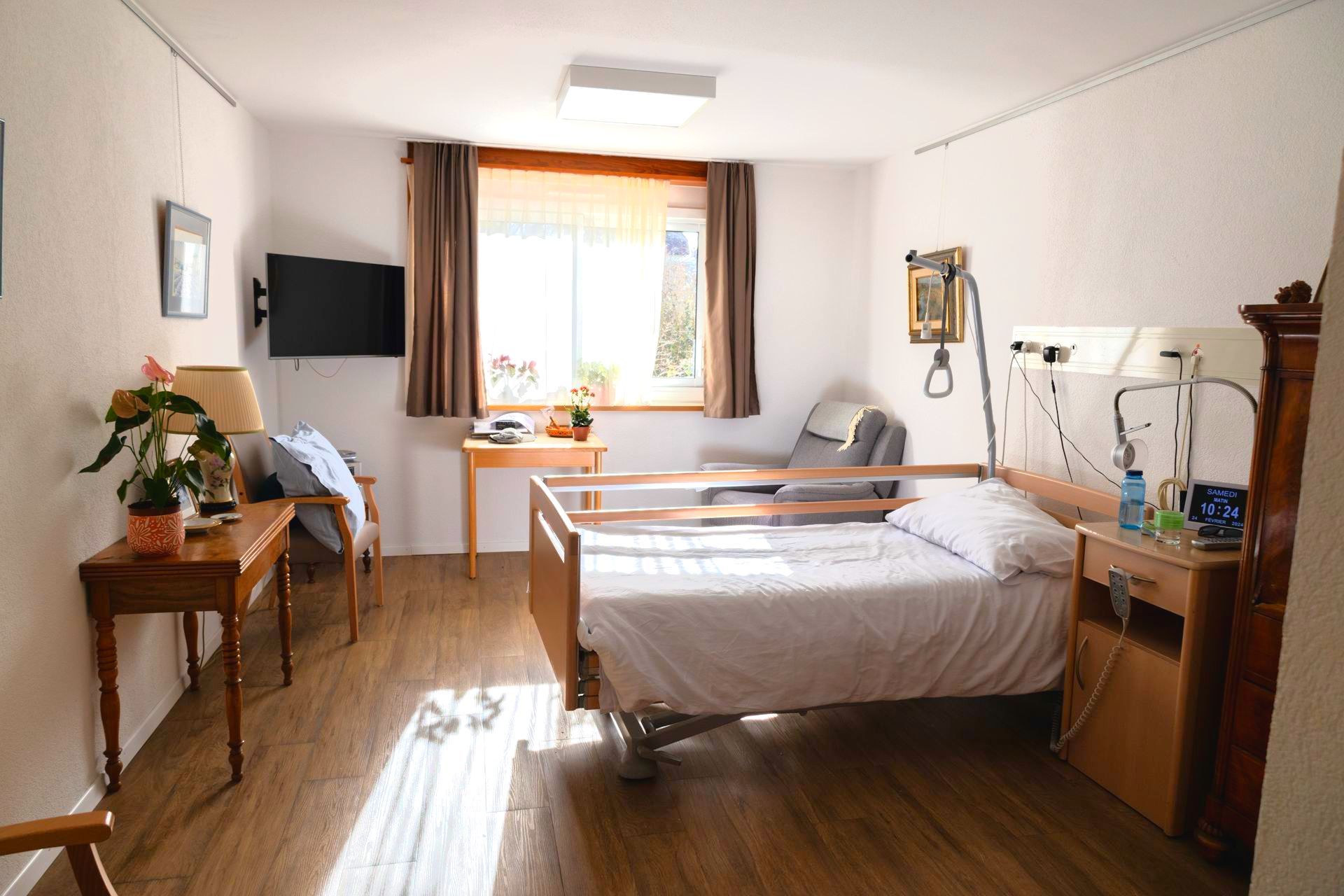 Une chambre ensoleillée avec une télévision écran plat au mur.