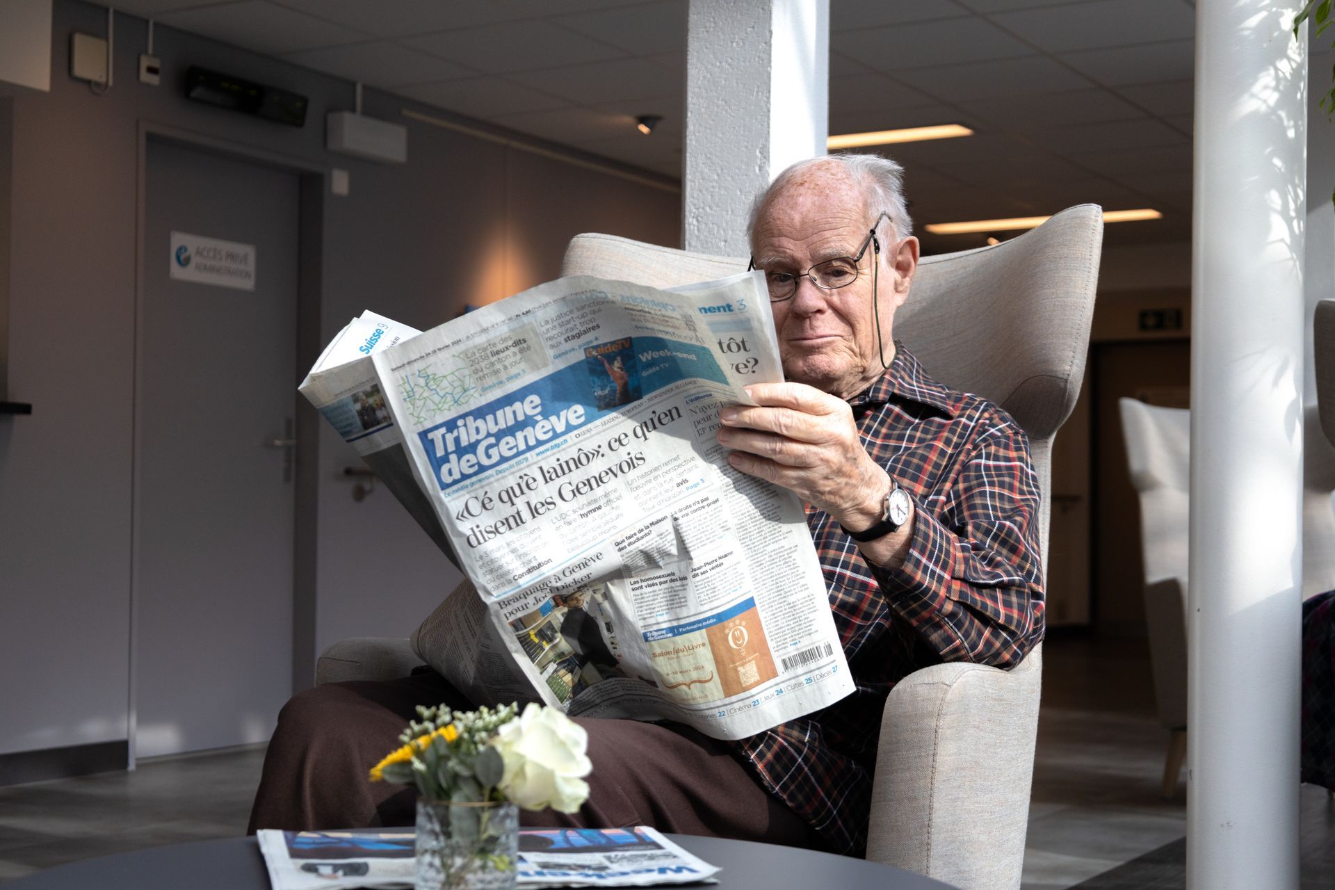 Une femme âgée bien apprêtée est assise à une table sous une tonelle.