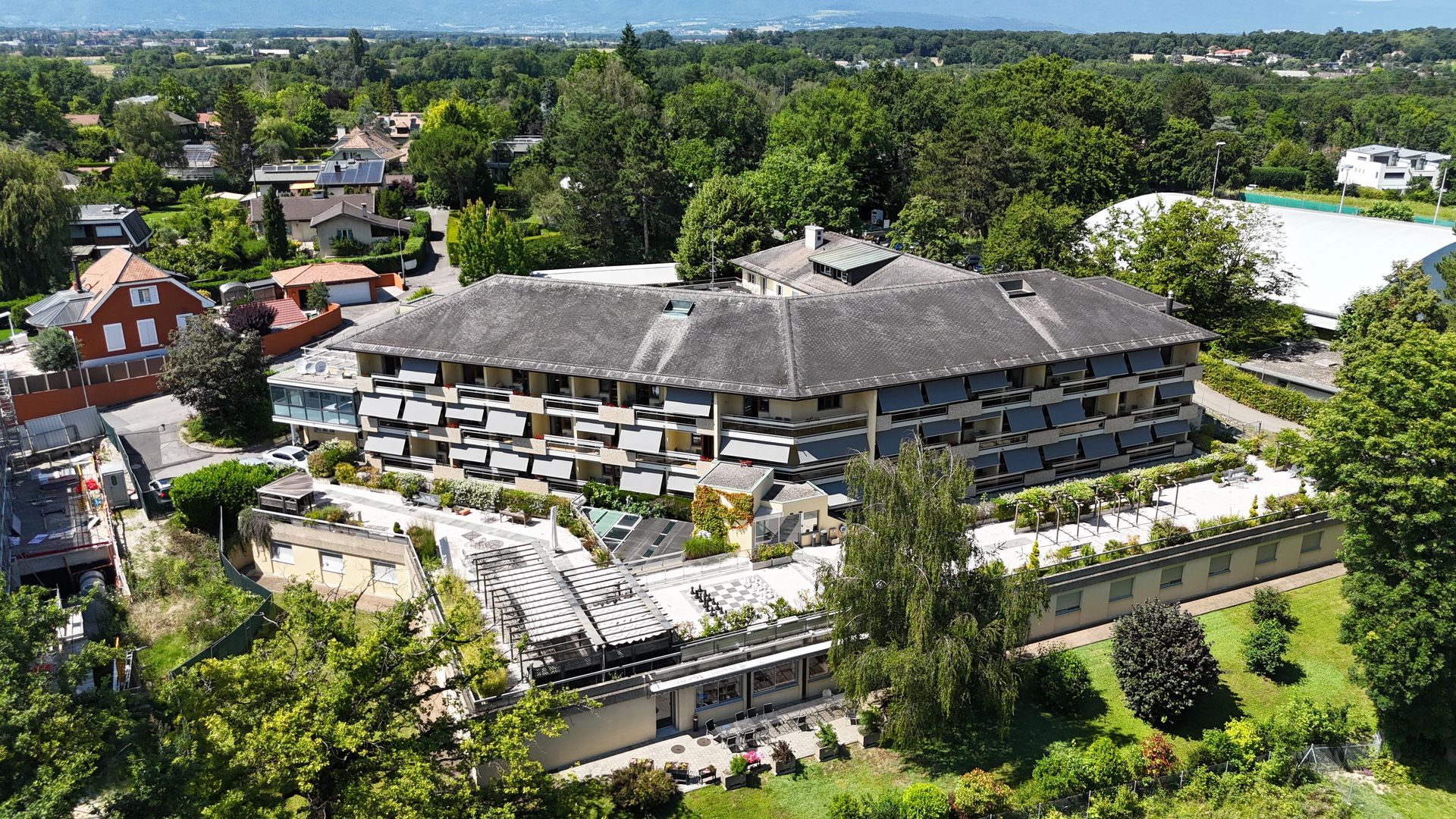 Une vue aérienne d'un grand bâtiment entouré d'arbres et de maisons.