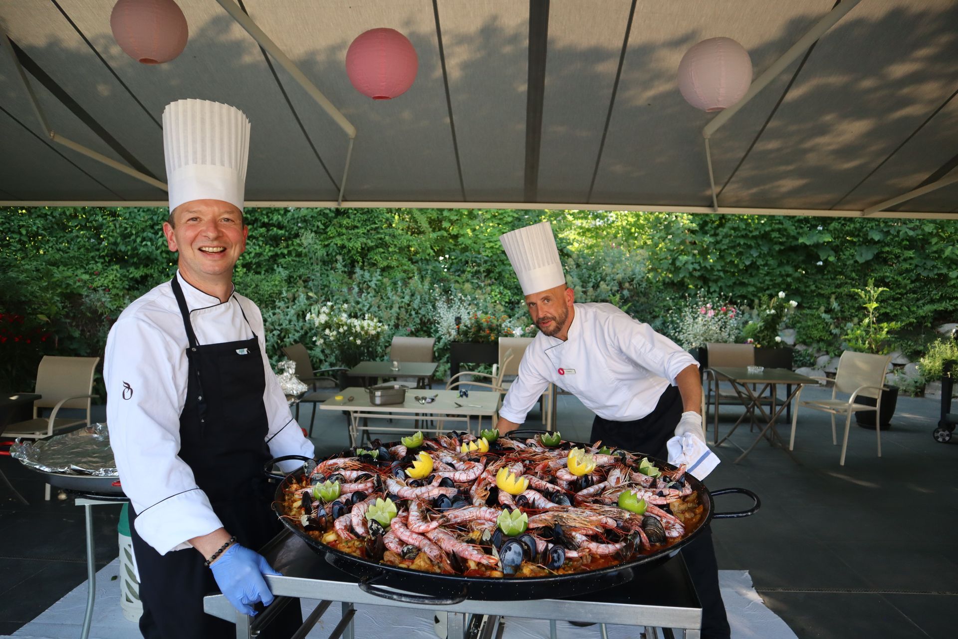Deux chefs se tiennent à côté d'une grande casserole de nourriture.