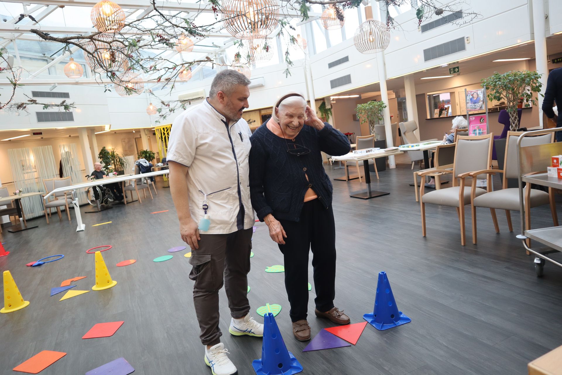 Deux hommes se tiennent à côté d'un homme âgé dans une pièce.
