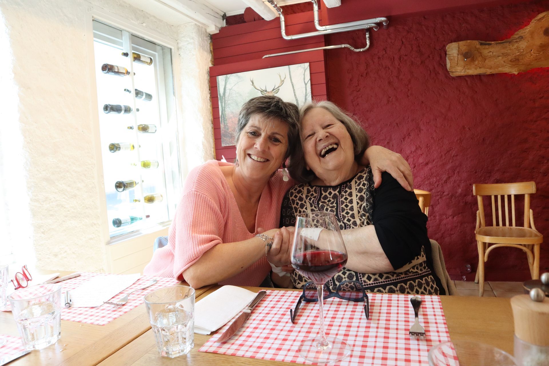 Deux femmes sont assises à une table avec un verre de vin.