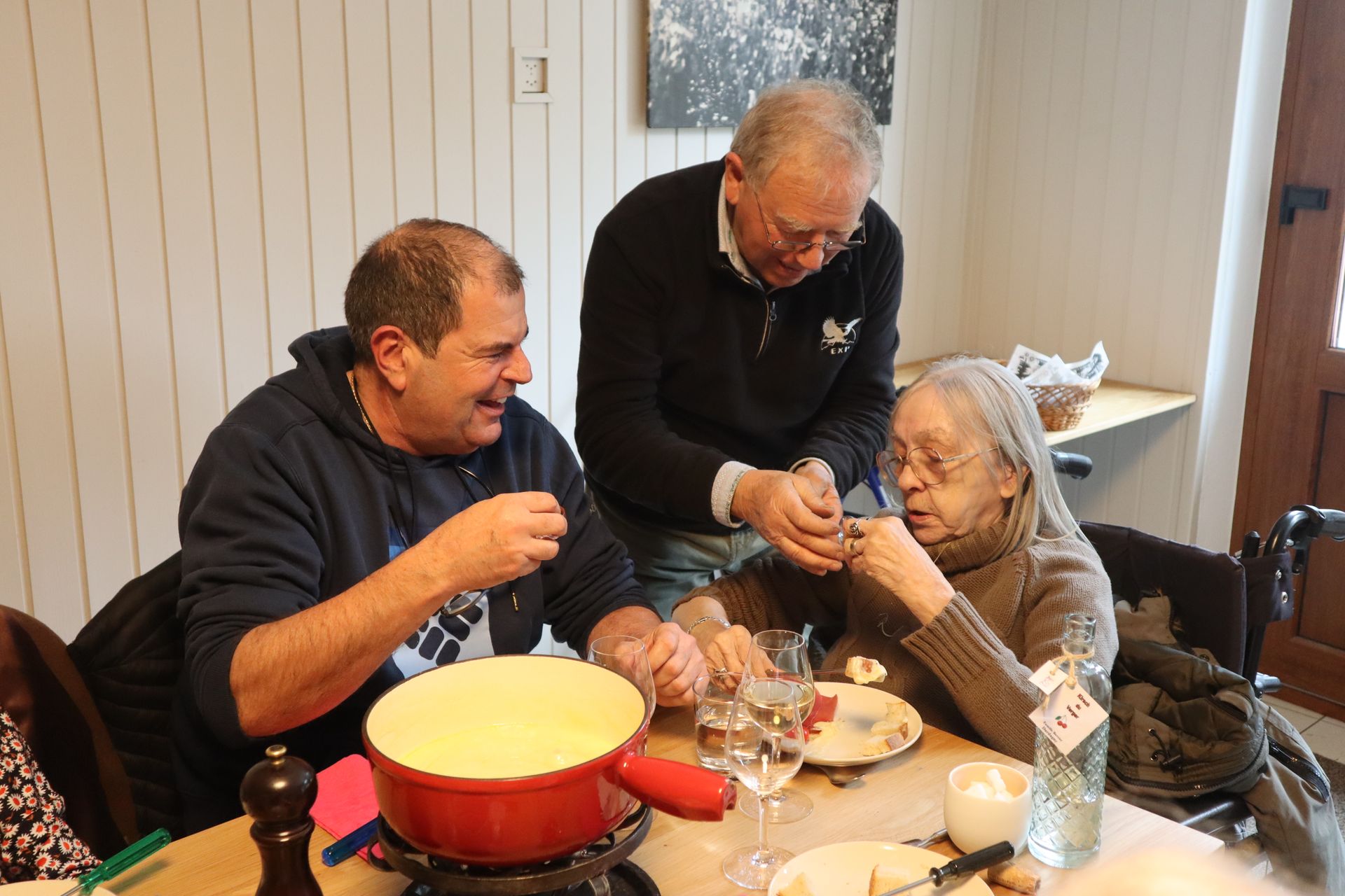 Un groupe de personnes sont assises à une table en train de manger de la fondue.