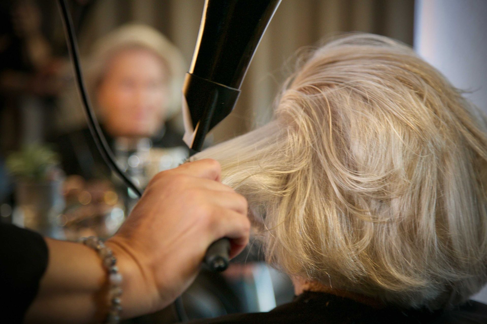 Une femme se fait sécher les cheveux par une coiffeuse.