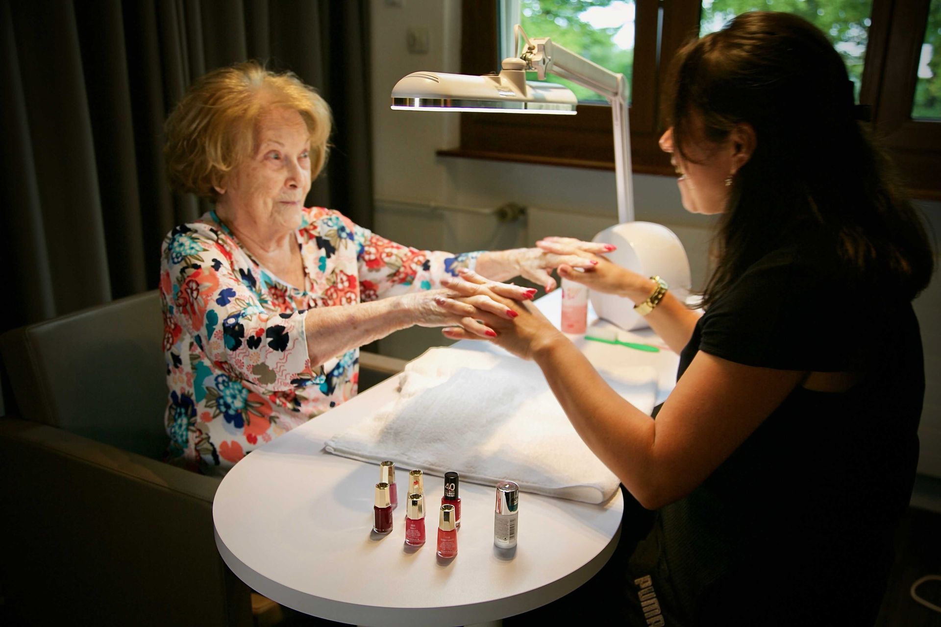 Une femme réalise une manucure à une femme plus âgée.