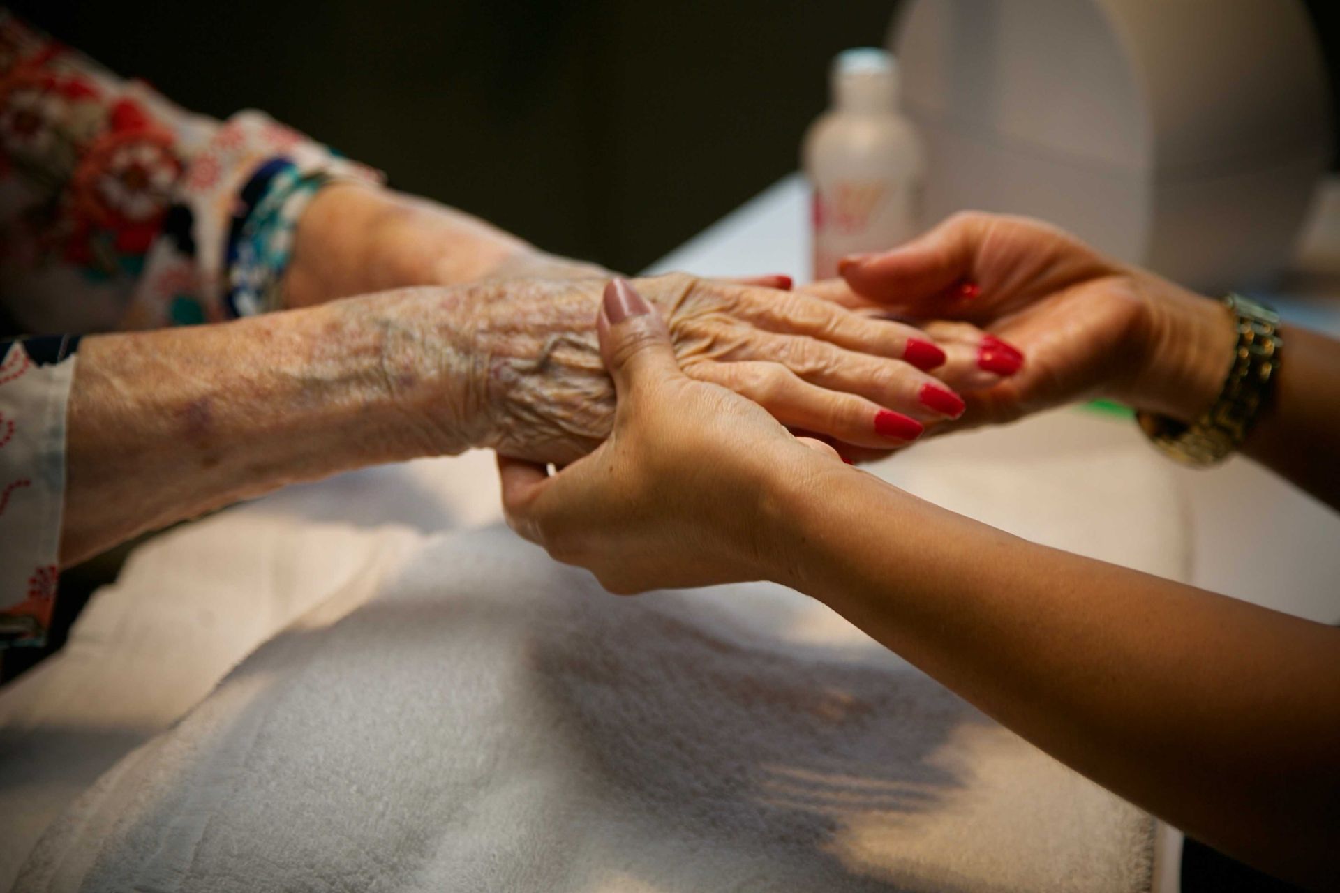 Focus des mains d'une femme qui réalise une manucure à une femme âgée.
