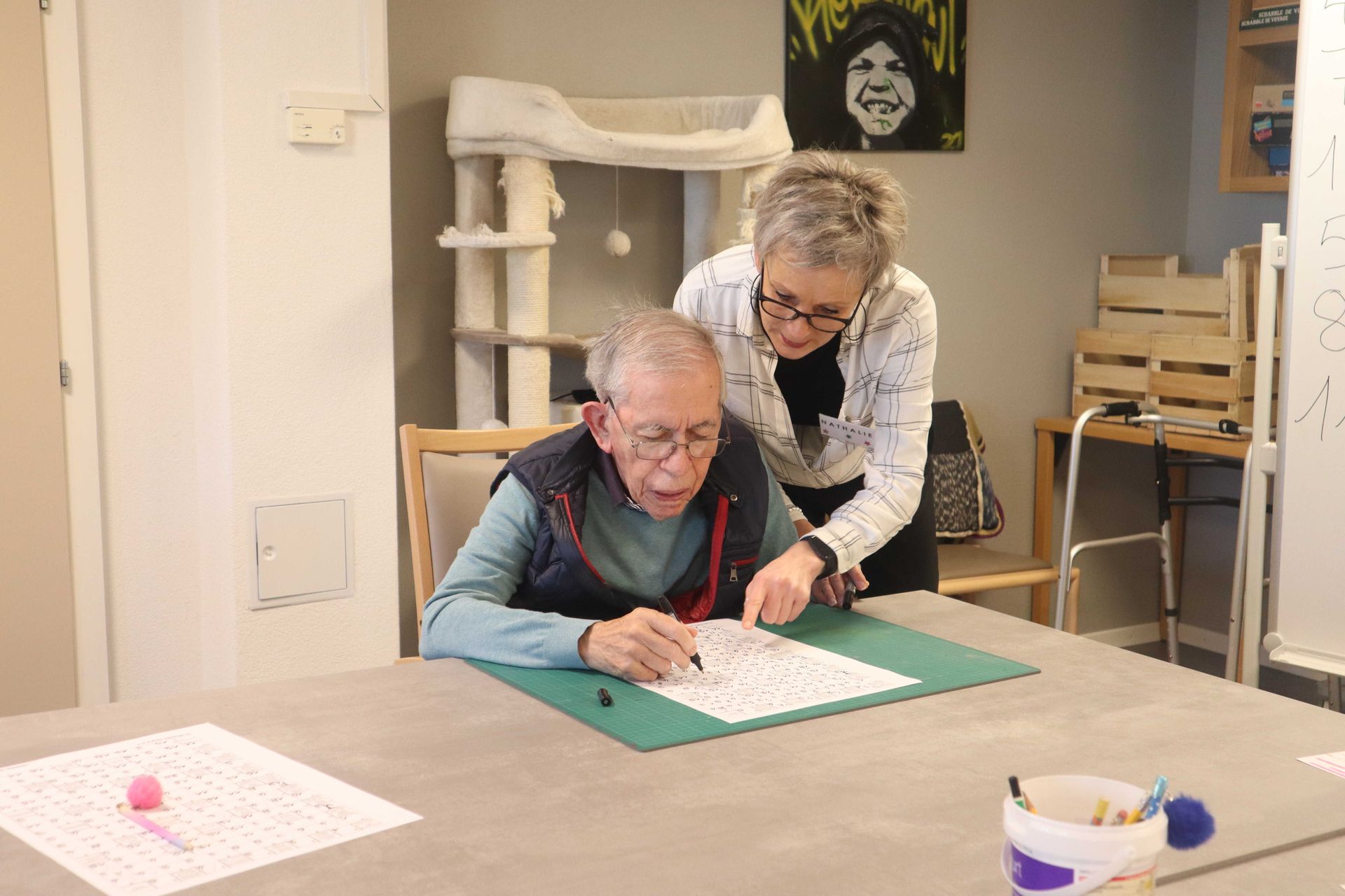Une soignante se tient à côté d'une femme âgée en fauteuil roulant.