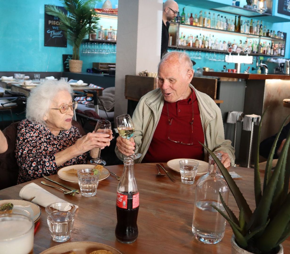 Un homme et une femme sont assis à une table avec une bouteille de Coca Cola