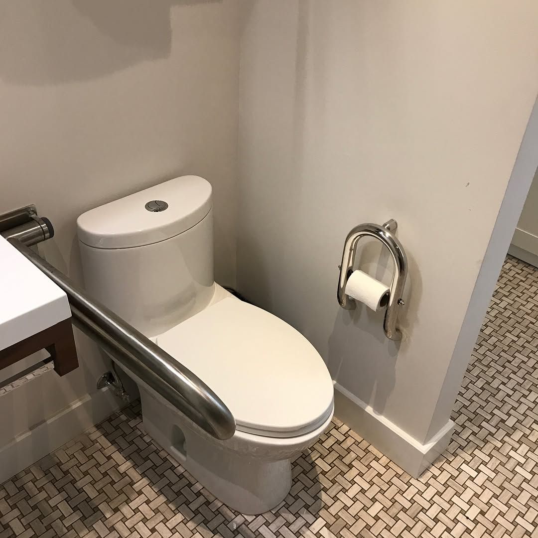 Une salle de bain avec toilettes, lavabo et porte-papier toilette.