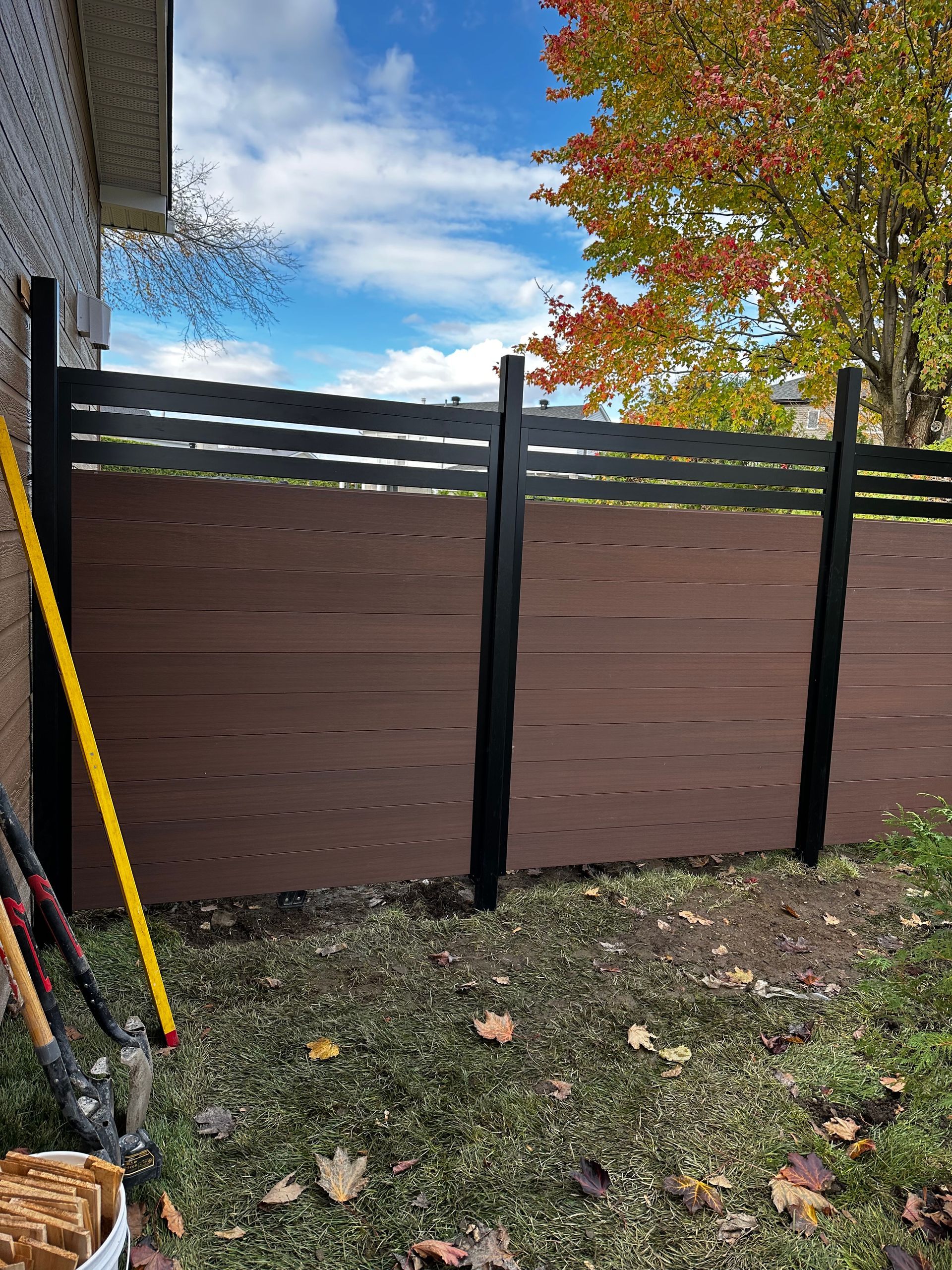 Une clôture en bois est en train d'être construite dans l'arrière-cour d'une maison.