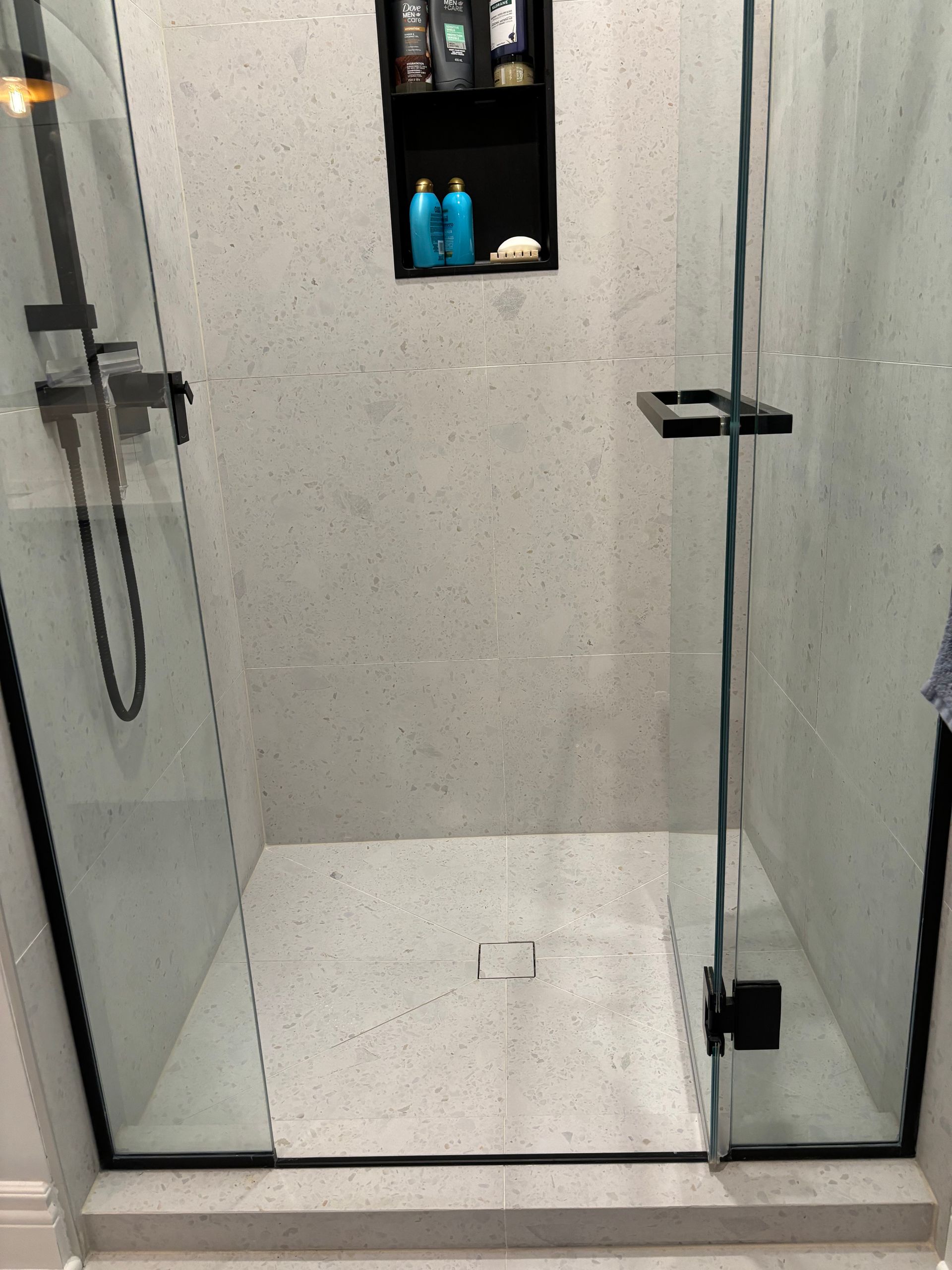 Une salle de bain avec une douche à l'italienne avec une porte vitrée